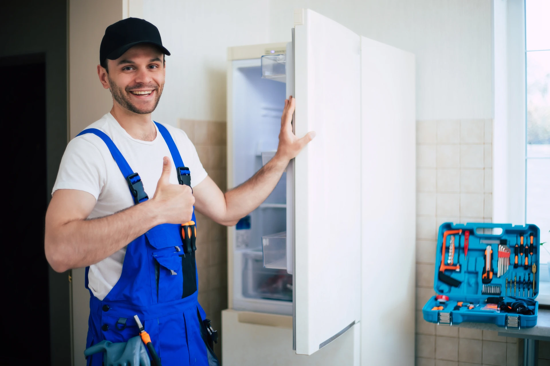 professional-young-repairman-worker-uniform-cap-with-modern-toolbox-with-equipment-after-repair-refrigerator-kitchen